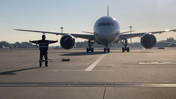 飛行機を所定の位置へ導くマーシャリングの様子。プッシュバックに限らず、こうした一つ一つの地上業務が連携することで、安全で確実な運航が実現している